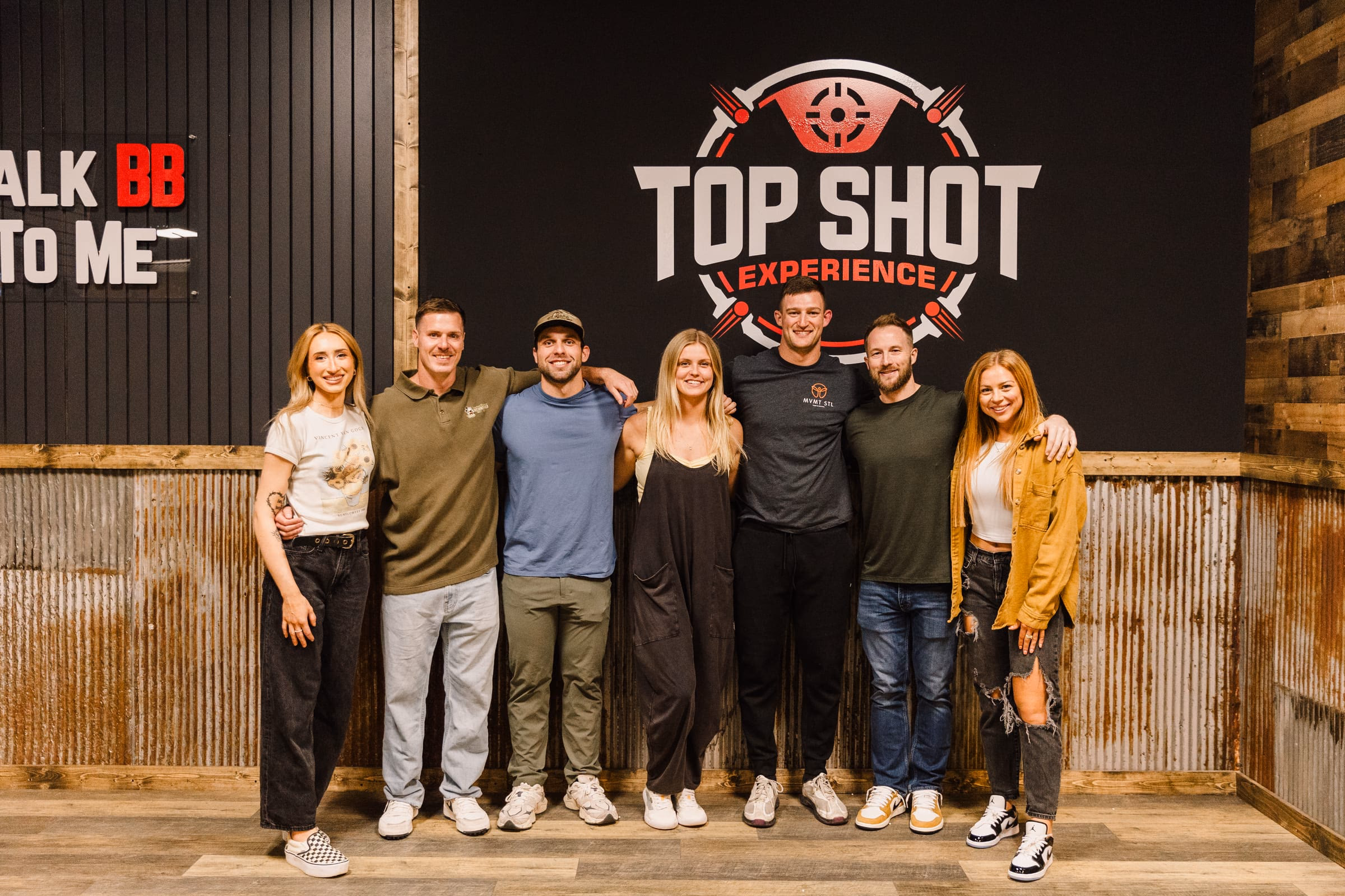 A group of guests together in front of the Top Shot Experience wall