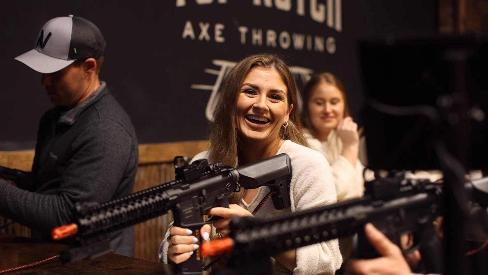Two guests laughing behind the rifle at Top Shot